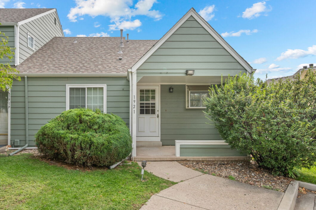 Green townhouse entrance with shrubs and walkway